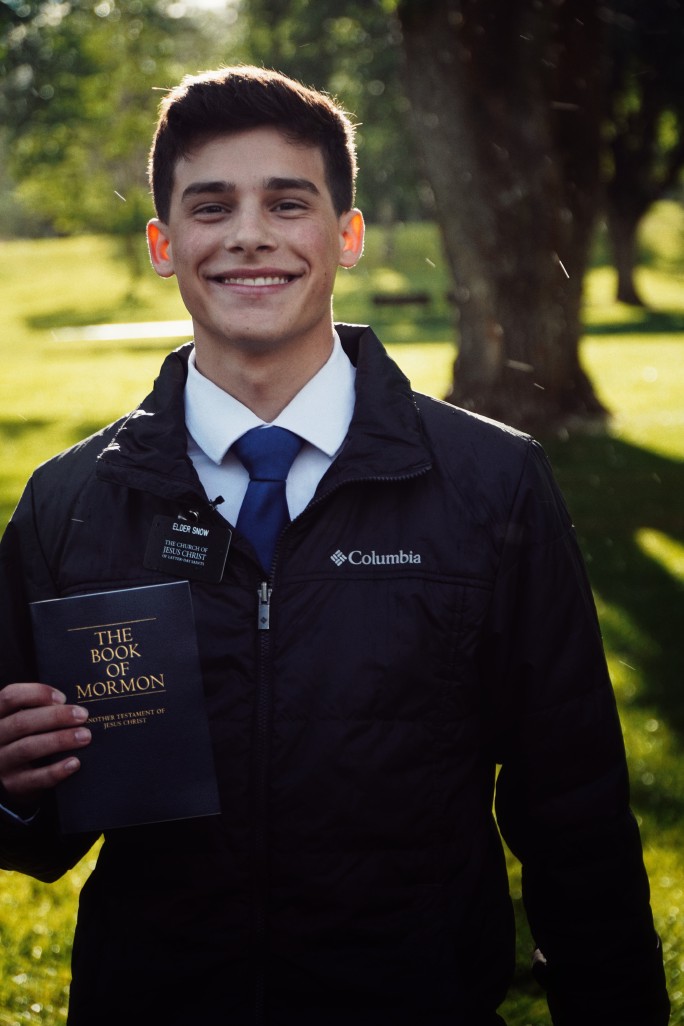 Elder Snow holding a book of mormon in the rain